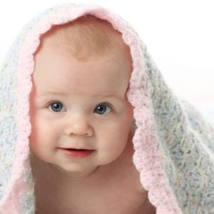 8558051 - cute baby girl lying on her tummy with a hand crocheted blanket over her head